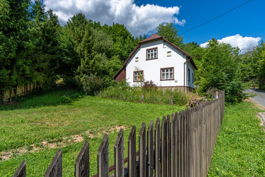 Rural house with wooden fence in lush green nature
