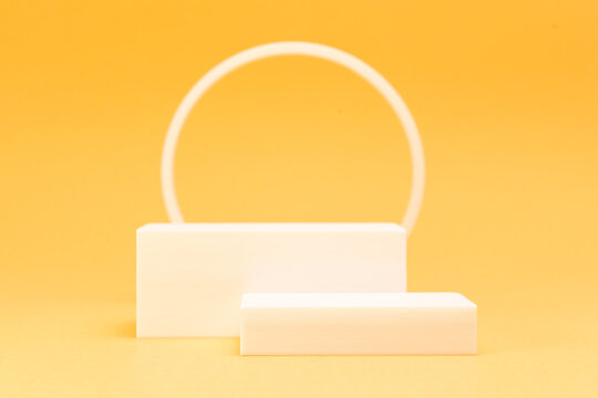 Minimalist white rectangular podiums with circle frame on warm yellow background