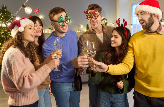 Friends toasting champagne at a Christmas party. Laughter and cheers fill the home as friends clink flutes by a tree and festive lights. Joyful holiday celebration with close friends.