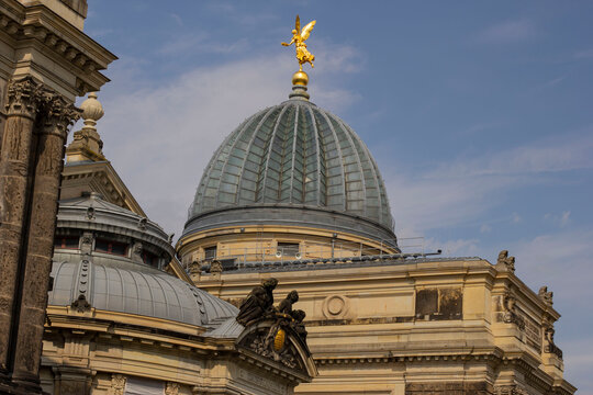 The glass dome of the Dresden Academy of Fine Arts (Kunstakademie), known as the Lemon Squeezer, topped with the golden statue of Pheme. Blue sky with copy space, Dresden, Germany