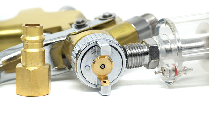Close-up of a professional airbrush gun with brass and chrome components
