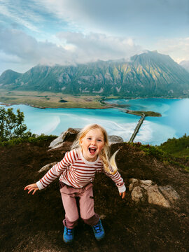 Child girl having fun travel in Lofoten islands family vacations in Norway outdoor hiking summer activity 5 years old kid excited face expression enjoying aerial view from Matmora mountain