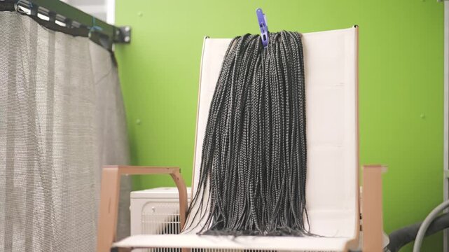 Synthetic box braid extensions hanging to dry on a balcony chair