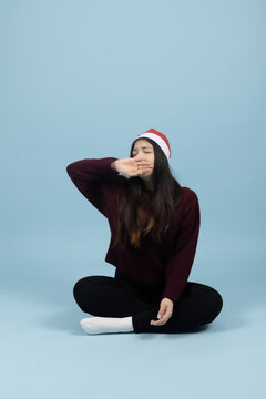 Confused woman in santa hat shrugging her shoulders displaying positive emoti...