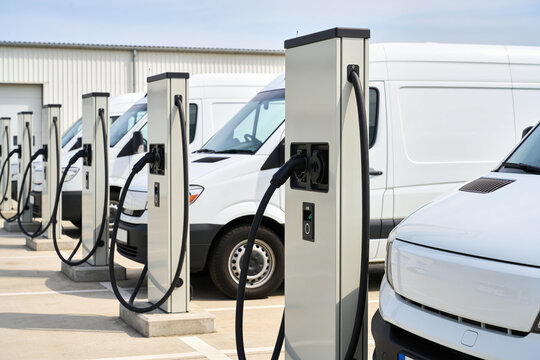 Fleet of electric vans charging at modern charging stations in a row