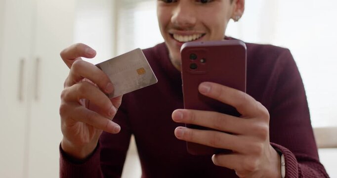 African American adult male angling EMV card and tapping purple phone smiling in home kitchen