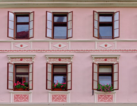 Pink wall of a renewed XVIc.house on Mestni trg E side of white and red cornices, moldings, pediments, plus flowery windows. Skofja Loka-Slovenia-150