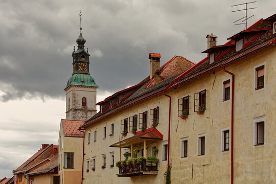 St.Jacob church bell tower projecting into the overcast sky while jutting from the buildings on Blazeva ulica street N side. Skofja Loka-Slovenia-161