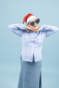 Young woman with hands behind her head smiling happily on blue wall