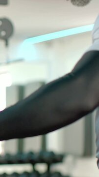 Vertical video: Placing hands on handlebars, man doing arm rows for cardio at gym in gray shirt