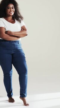 Vertical video: Smiling model moving with camera rolling, shifting in studio, white tee and jeans