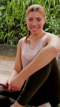 Vertical video: Reading message, woman on mat smiling, laughing in studio, holding phone, in tank
