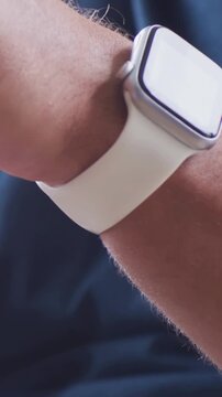 Vertical video: Rotating left wrist adjusting square watch after glare at home showing white band