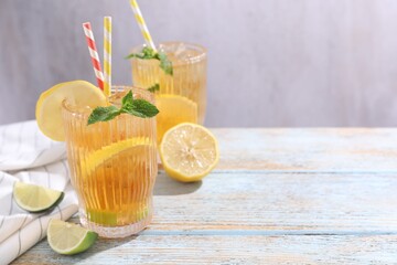 Fototapeta premium Refreshing ice tea with lemons, lime and mint on wooden table, closeup. Space for text