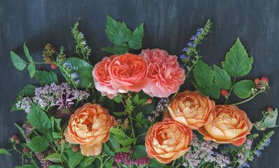 Garden bouquet with coral and orange English roses, yarrow, wildflowers and raspberry branches on dark background © kulikovan