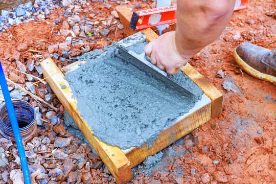 Worker prepares concrete mix in wooden form on construction site