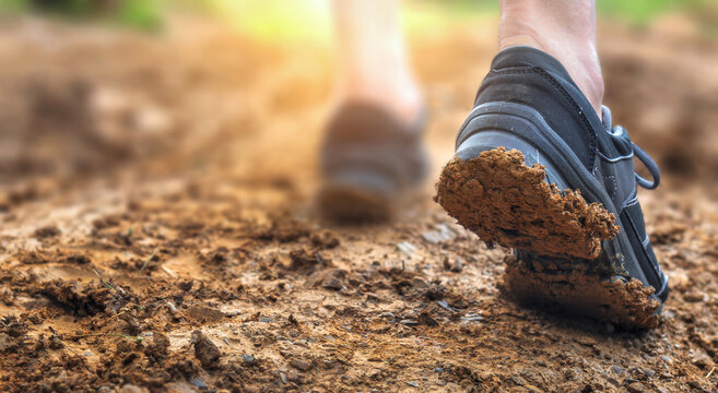 Dirty hiking boots walking on muddy trail