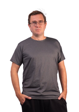 A white male model wearing a short-sleeved, shiny, heather-gray polyamide sports shirt and sweatpants, with one hand in his pocket; he is wearing glasses.