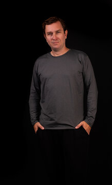 White male model wearing a long-sleeved, graphite-grey heather, shiny polyamide sports shirt against a black background.