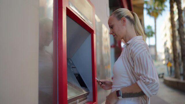 Woman inserting bank card into outdoor ATM to withdraw cash. Secure banking transaction, personal finance, cash access and modern financial services concept.
