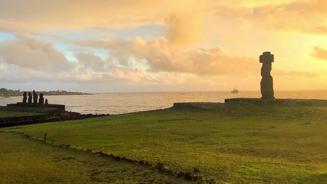 Ahu Tahai ceremonial complex on Easter Island, Chile. Historic Moai statues overlooking the Pacific Ocean on the sunset with scattered clouds.