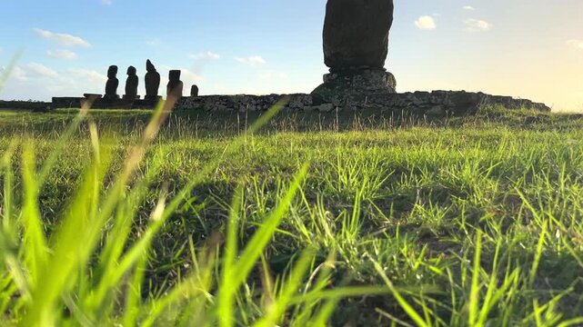  Ahu Tahai ceremonial complex on Easter Island, Chile. Historic Moai statues overlooking the Pacific Ocean on the sunset with scattered clouds.