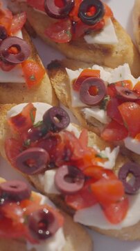 Bruschetta with tomato, mozzarella, olives and dark sauce is shown in close up