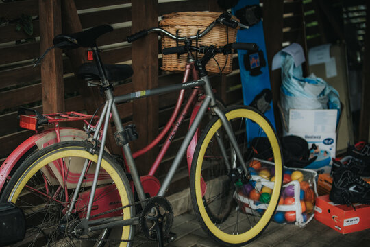 Madona, Latvia - July 11, 2026: Bicycle with yellow wheels and basket parked beside a pink bike in a cluttered storage area filled with various items