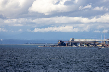Naklejka premium Industrial Waterfront Conveyor Pier Along Stormy Coastline With Clouds Over Ocean Near Tsawwassen, British Columbia, Canada