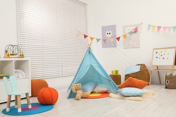 Beautiful wigwam with soft pillows, toys and magnetic board in child's room © New Africa