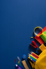 Back to school vertical supplies flat lay with colorful pencils backpack magnifier and notebooks on...