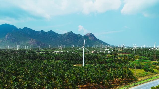 Wind turbines generating clean renewable energy across coconut plantation and mountains
