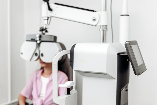 Young woman having her eyesight checked with a phoropter during an eye exam. Concept visual health, ophthalmology, preventive medicine, eye care, diagnostics.