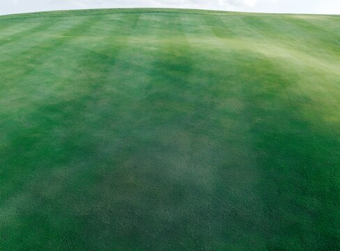 Vibrant Green Rolling Grass Landscape Featuring Mown Lawn Texture Under Natural Light Perfect for Outdoor Sports or Serene Garden Background Concepts
