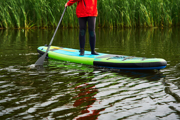 Active participants in life jackets standing on inflatable SUP boards. Dynamic water sports scene with people paddling together on a peaceful lake during a cloudy summer day. © Rabizo Anatolii