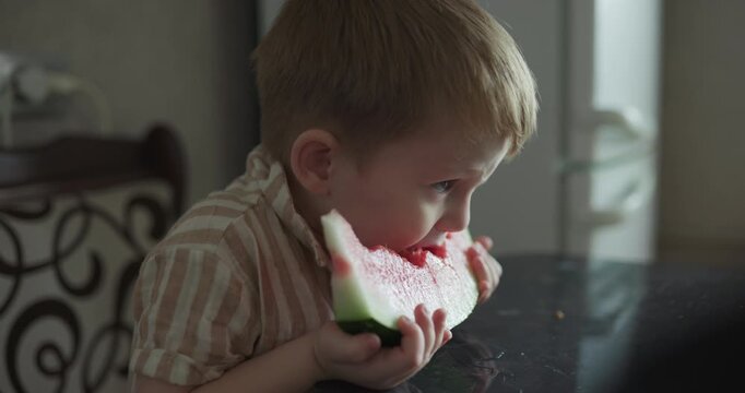 Young boy enjoying sweet watermelon fruit treat at the table