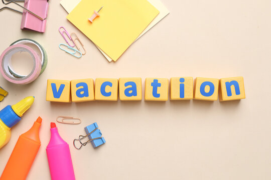 School holiday. Wooden cubes with word Vacation and stationery on beige background, flat lay