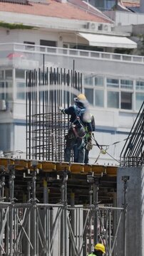 Workers build structure at construction site in city during daylight hours