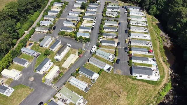 Aerial drone 4K clip showing caravans placed near meadow vegetation under warm daylight Wales