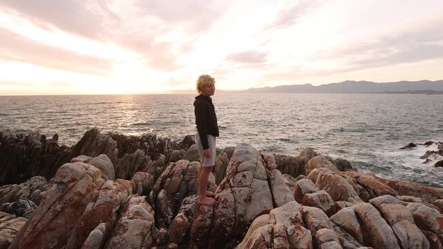 two boys exploring and hiking the spectacular rocky coastline of DeKelders, South Africa at sunset