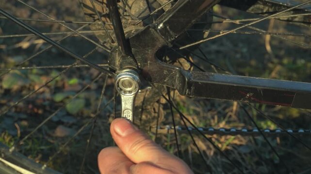 Mechanic adjusts bicycle crank using a wrench, showcasing detailed action progression in a natural outdoor setting with grass and dirt