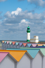 Fototapeta premium Views of ocean beach and colourful beach huts or cabins in Le Treport, seaside resort in Normandy, France, with white cliffs along English Channel, travel destination in France