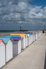 Fototapeta premium Views of ocean beach and colourful beach huts or cabins in Le Treport, seaside resort in Normandy, France, with white cliffs along English Channel, travel destination in France