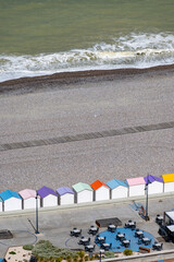 Fototapeta premium Views of ocean beach and colourful beach huts or cabins in Le Treport, seaside resort in Normandy, France, with white cliffs along English Channel, travel destination in France