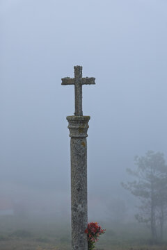 Stone cross rising from a misty cemetery