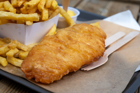 Fish and chips on Le Treport promenade &mdash; golden battered cod with mountain of french fries, seaside flavors enjoyed outdoors by the harbor in Normandy, France