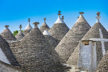 Close-up view of the distinctive conical limestone roofs and decorative whitewashed pinnacles of traditional trulli buildings in the historic Rione Monti district © erikzunec