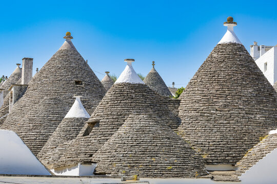 Close-up view of the distinctive conical limestone roofs and decorative whitewashed pinnacles of traditional trulli buildings in the historic Rione Monti district