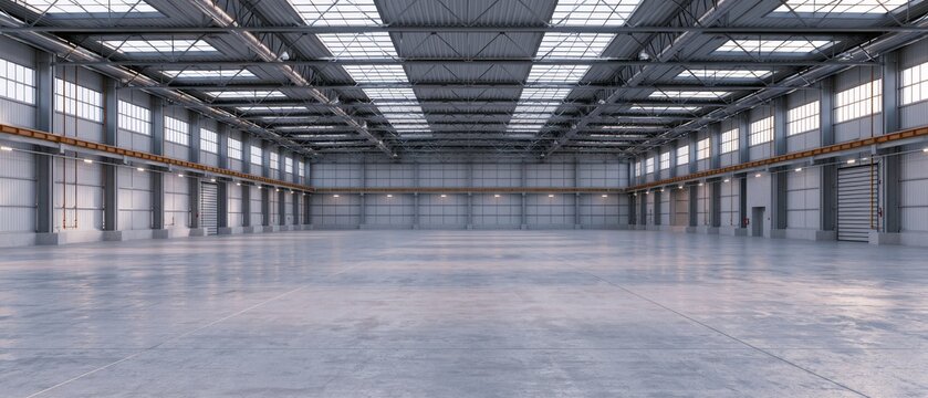 Empty warehouse interior with high ceilings and large windows during daylight