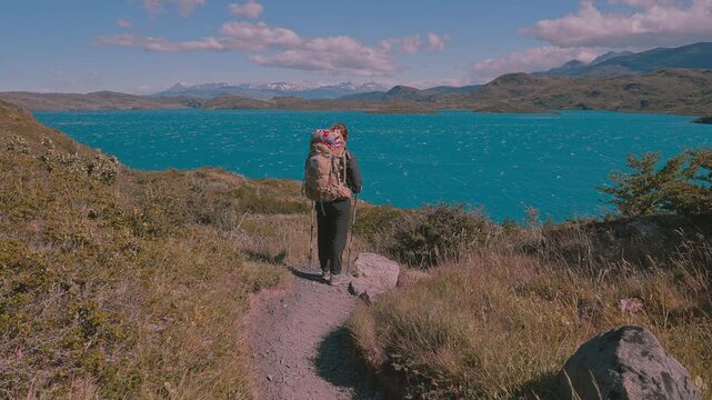 Moving toward rear view of standing hiker taking in the natural beauty of Torres del Paine on a sunny day, Patagonia, Chile